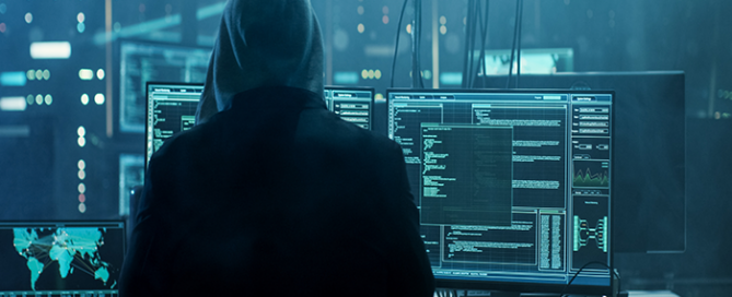 cyber hacker in hoodie in front of computers