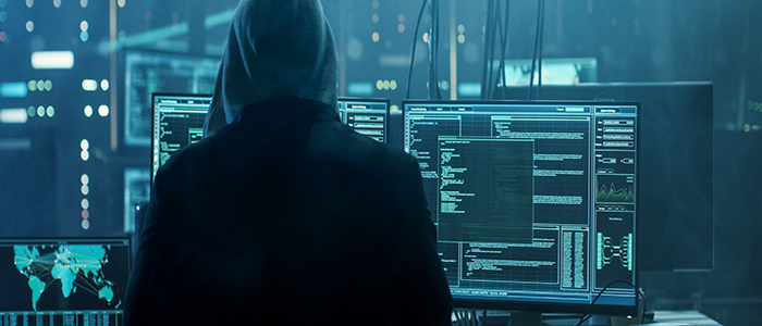 cyber hacker in hoodie in front of computers